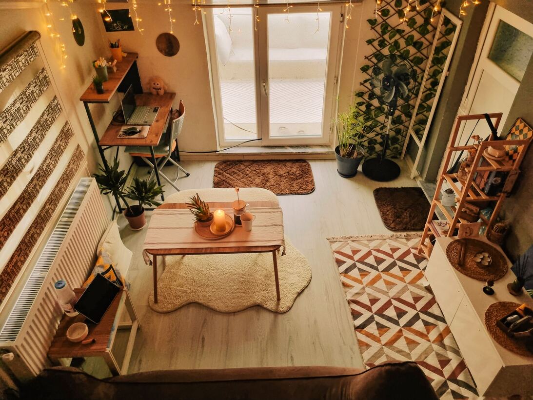 Studio apartment seen from above with a desk, rug and string lights