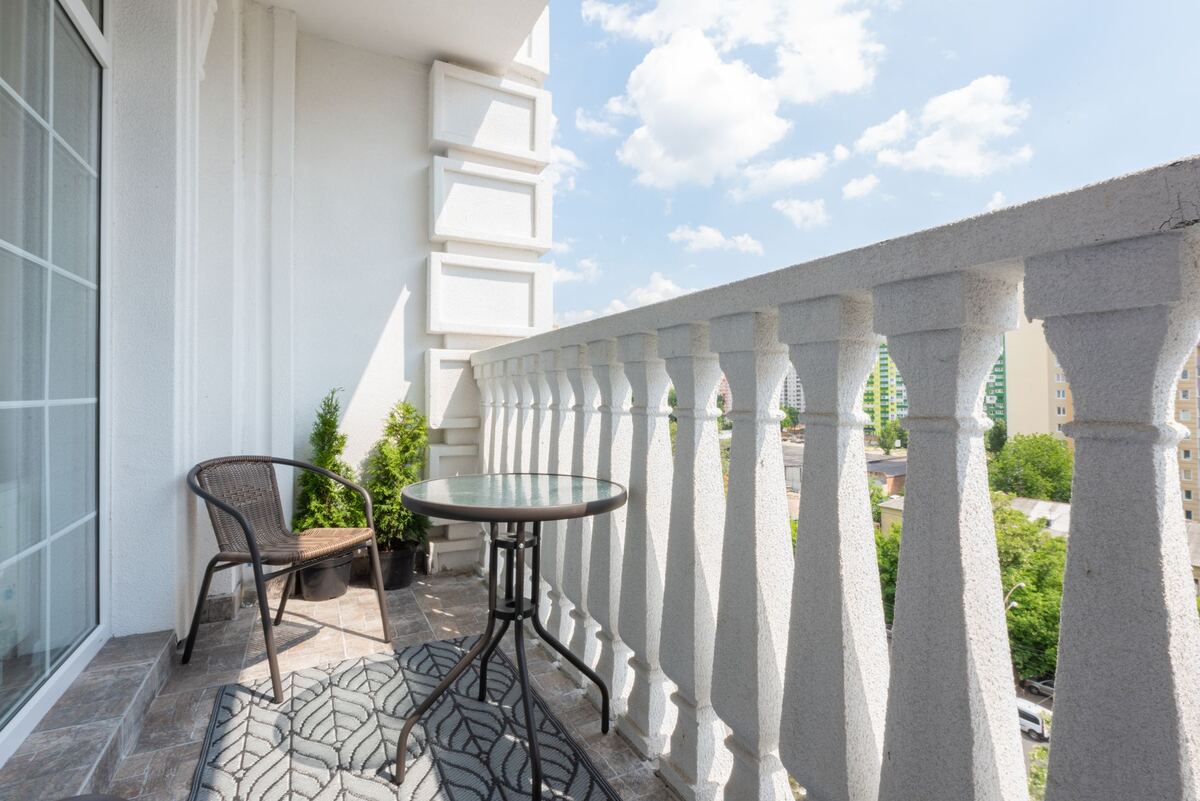 Small balcony table and chair above a leafy street