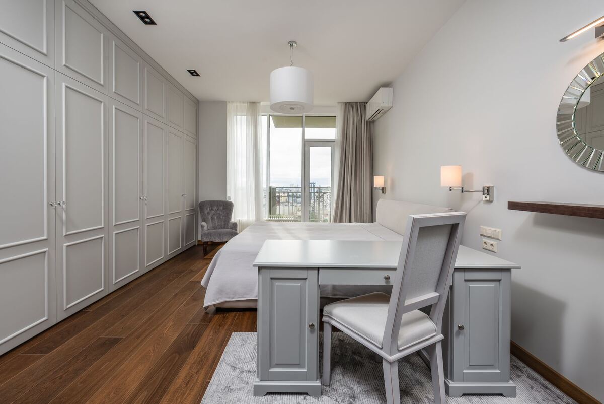 Bedroom with a writing desk and chair beside a balcony door