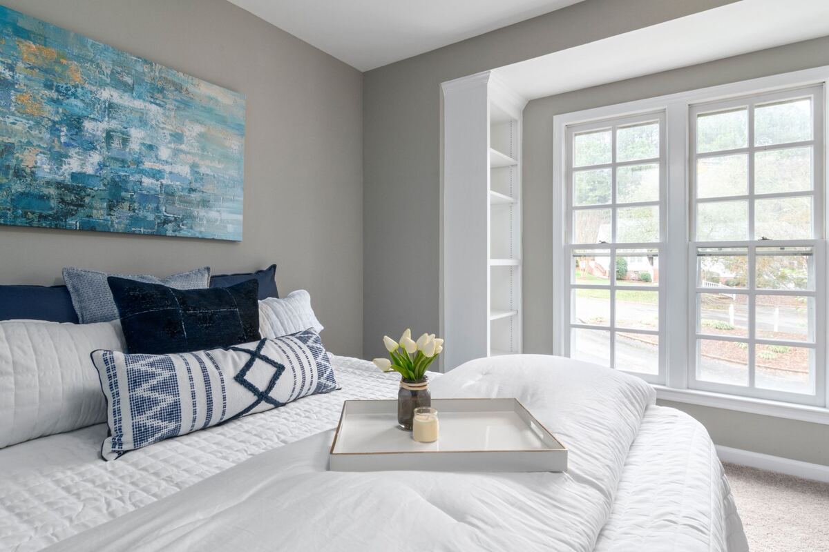 Bright bedroom with tall windows and white bedding