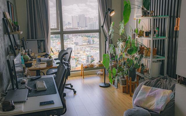 Corner workstation and houseplants beside a tall apartment window