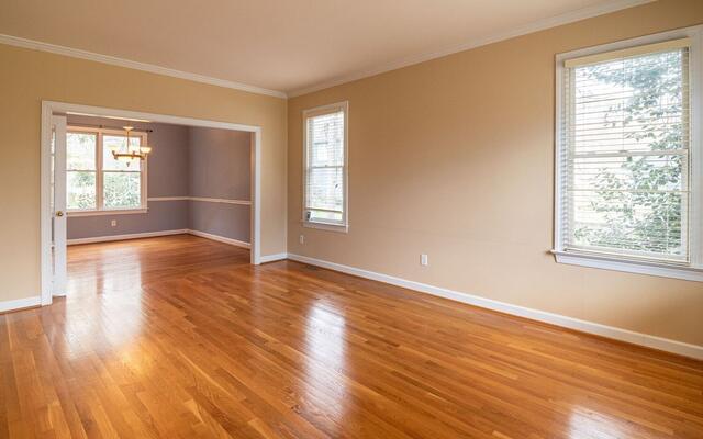 Empty apartment rooms with wood floors and daylight from two walls
