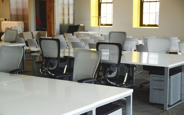 Open-plan office with rows of white desks and mesh chairs