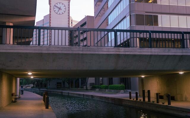 Quiet canal and walkway beneath a downtown San Antonio bridge