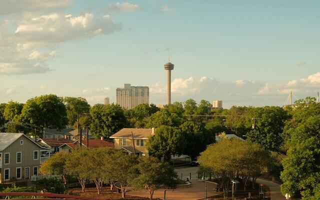 Footbridge and tree-shaded houses south of downtown San Antonio with the Tower of the Americas beyond
