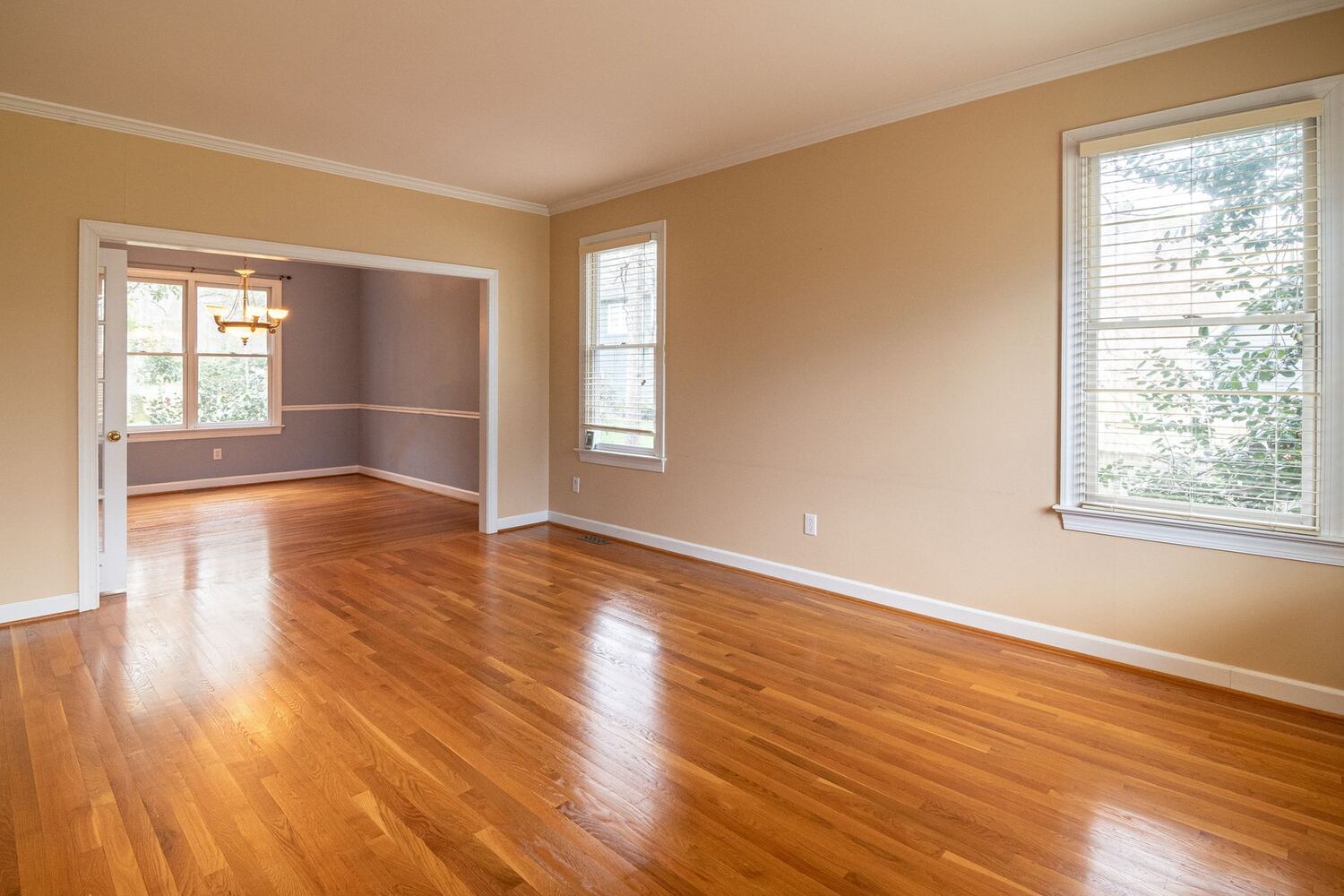 Empty apartment rooms with wood floors and daylight from two walls