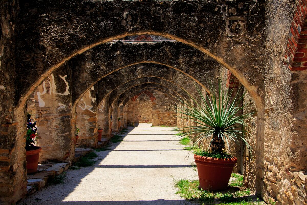Sunlit arched stone walkway at a San Antonio mission