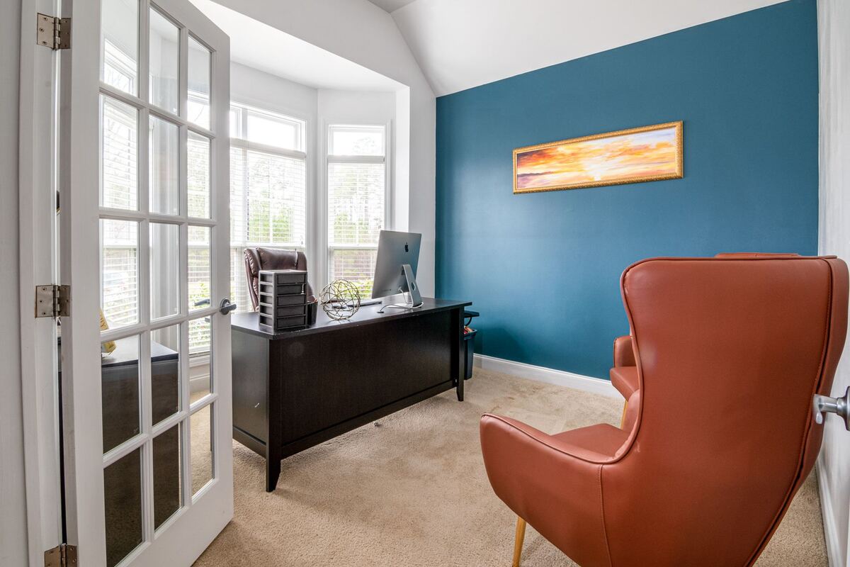 Home office behind French doors with a bay window and a desk