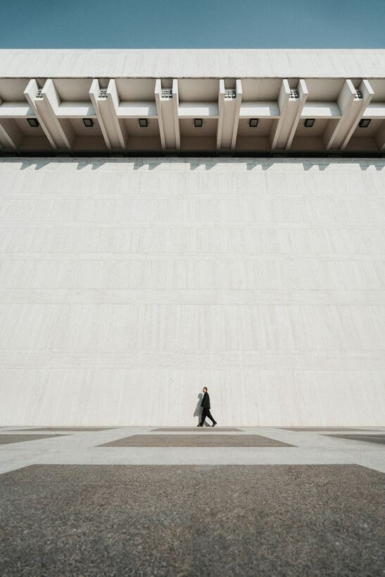 Wide empty plaza beneath a long concrete wall