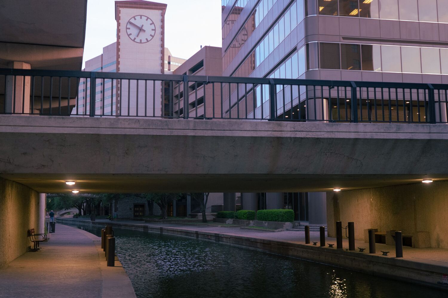 Quiet canal and walkway beneath a downtown San Antonio bridge