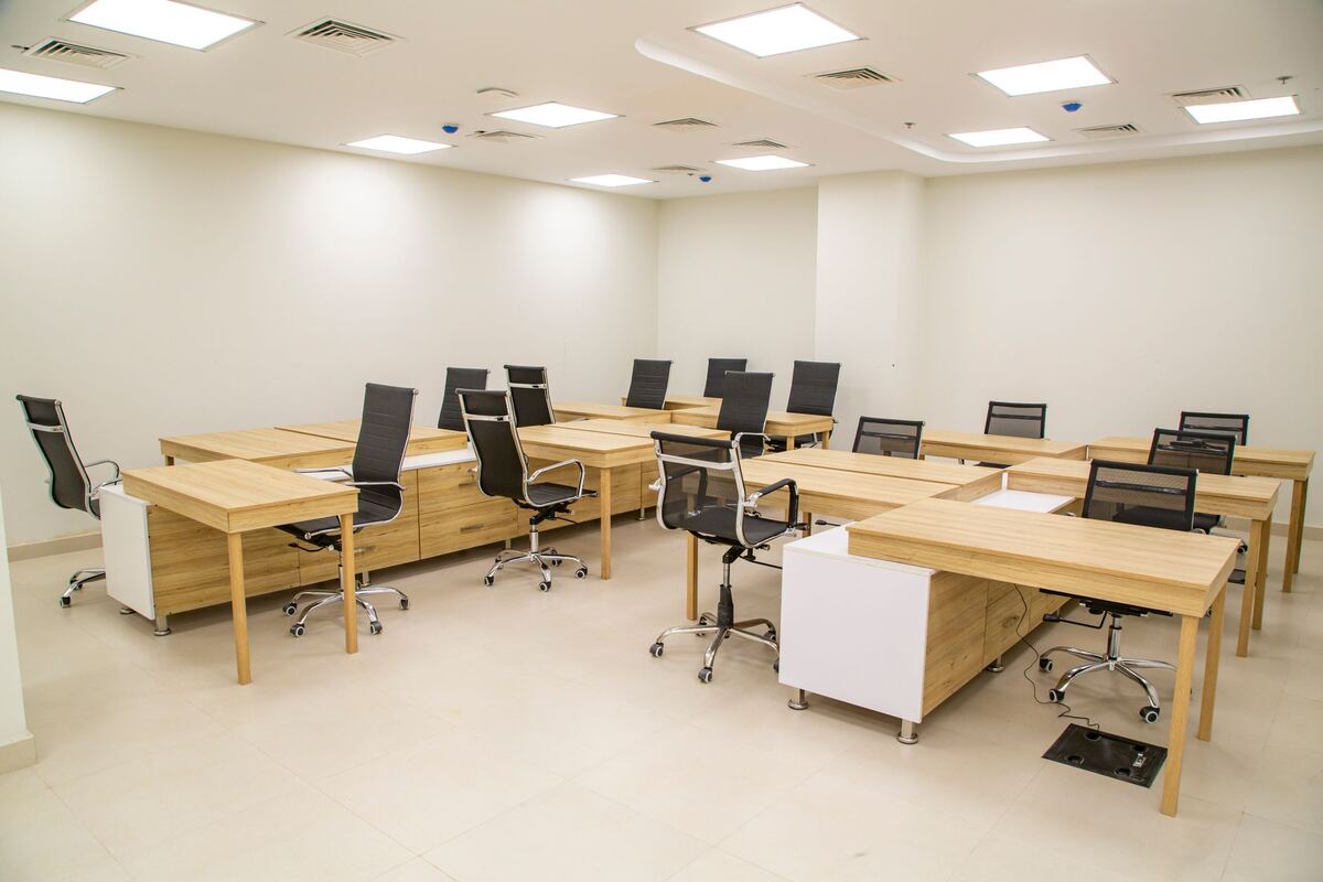 Shared office room lined with wooden desks and task chairs