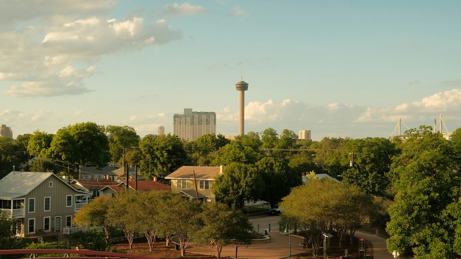 Footbridge and tree-shaded houses south of downtown San Antonio with the Tower of the Americas beyond