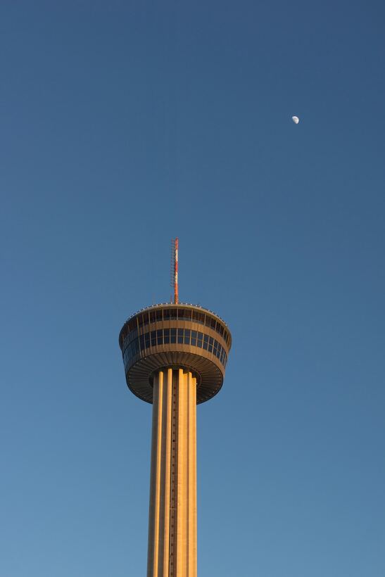 Tower of the Americas lit by late sun with the moon above San Antonio